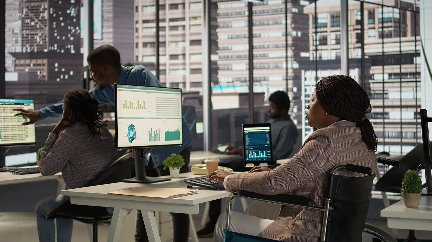 Темнокожий менеджер, использующий инвалидную коляску, просматривает финансовые данные для ежемесячных отчетов.